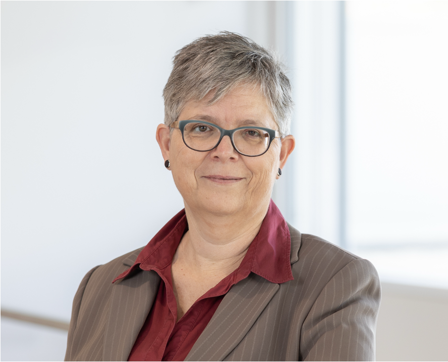 eine Frau mit Brille und einer roten Bluse und braunen Blazer