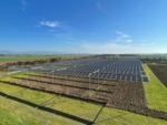 hoch aufgeständerte Photovoltaik-Module im Hintergrund mit Blick auf die Landschaft.